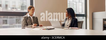 Une réunion d'affaires collaborative entre deux professionnels se déroulant dans un espace de bureau moderne Banque D'Images