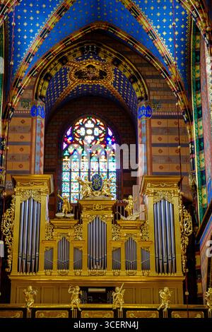 Orgue à grande pipe de la basilique Marie de Cracovie, en Pologne, avec des pipes plaquées or et des sculptures complexes, sur fond de colorfu Banque D'Images