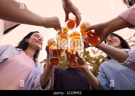 Groupe d'amis heureux clinquant des verres de bière à l'extérieur, vue de dessous Banque D'Images