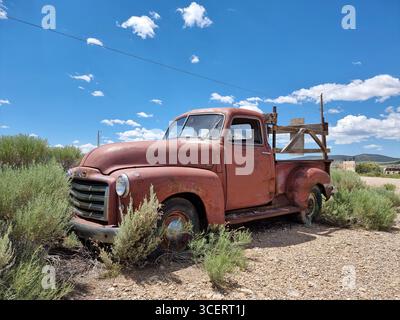 Vieille voiture usagée rouillée le long d'une route non pavée dans la prairie du Nouveau-Mexique ; camionnette rouge GMC ; camion rouillé ; camion rouge GMC ; camion rétro GMC Banque D'Images