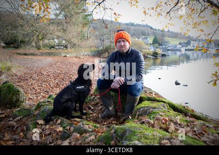 Paul Leonard , chef cuisinier au restaurant Michelin Star Forest Side à Grasmere en Cumbria avec son chien sur les rives du lac Windermere dans le lac D. Banque D'Images