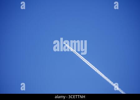 Avion à réaction laisse traîner à travers un ciel bleu clair et impeccable Banque D'Images
