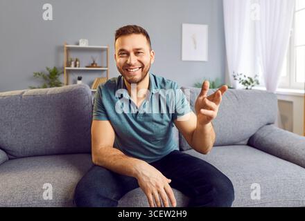 Heureux beau jeune blogueur homme à la maison parlant à la caméra, donnant vente formation webinaire, en ligne Banque D'Images