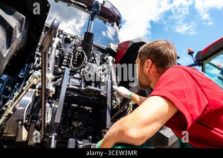 Vue en bas angle d'un mécanicien de machines agricoles se tenant près d'un tracteur agricole Banque D'Images