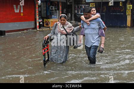 Mumbai, Maharashtra, Inde. 19 août 2025. Un homme porte son fils sur son dos alors qu'ils traversent une rue inondée causée par de fortes pluies à Mumbai. Le trafic sur la route, la ligne de chemin de fer ont été retardés en raison de fortes pluies et des inondations sur la route et la voie ferrée sont apparues. Les écoles et les collèges sont restés fermés et de nombreux bureaux ont permis à leurs employés de travailler à domicile. Alerte rouge a été émise par le Département météorologique indien (IMD) avertissant de précipitations extrêmement fortes jusqu'à mercredi, les citoyens ont été informés de ne pas s'aventurer dehors sauf si nécessaire. (Crédit image : © Ashish Vaishnav/SOPA images via ZUMA Press Wire) ÉDITEUR Banque D'Images