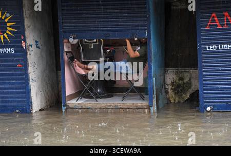 Mumbai, Maharashtra, Inde. 19 août 2025. Un homme vérifie son téléphone portable dans son magasin inondé d'eau causée par de fortes pluies à Mumbai. Le trafic sur la route, la ligne de chemin de fer ont été retardés en raison de fortes pluies et des inondations sur la route et la voie ferrée sont apparues. Les écoles et les collèges sont restés fermés et de nombreux bureaux ont permis à leurs employés de travailler à domicile. Alerte rouge a été émise par le Département météorologique indien (IMD) avertissant de précipitations extrêmement fortes jusqu'à mercredi, les citoyens ont été informés de ne pas s'aventurer dehors sauf si nécessaire. (Crédit image : © Ashish Vaishnav/SOPA images via ZUMA Press Wire) USAGE ÉDITORIAL Banque D'Images