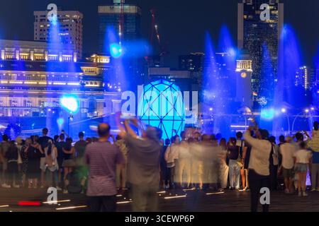 Les touristes utilisent leurs téléphones pour filmer l'enregistrement du spectacle de lumière et de son Spectra, magnifique fontaine d'eau à Marina Bay Sands, Singapour. Banque D'Images