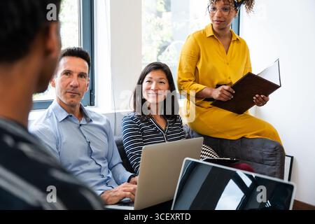 Des collègues travaillent en collaboration sur un projet, travaillent en équipe, utilisent des ordinateurs portables et discutent d'idées lors d'une réunion de bureau productive dans un Banque D'Images