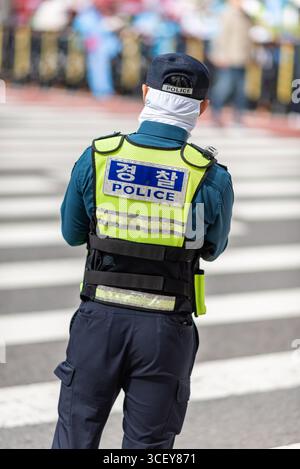 Un policier portant un gilet réfléchissant se tient à un passage pour piétons à Séoul, en Corée du Sud, le 9 octobre 2023 Banque D'Images