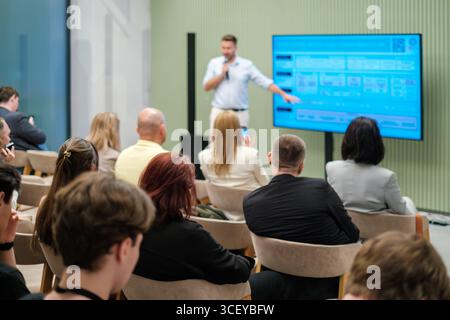 Conférencier donnant une présentation au public dans une salle moderne avec un grand écran. Banque D'Images