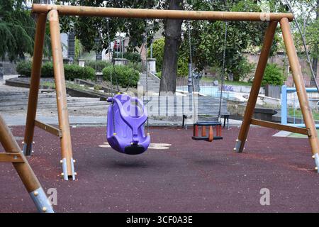Aire de jeux pour enfants avec balançoires en Italie. L'aire de jeux est entourée d'arbres et de maisons. Banque D'Images