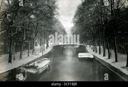 Une scène hivernale à Amsterdam, montrant le Reguliersgracht depuis le pont sur le Keizersgracht, regardant vers le Prinsengracht. La photo a été prise en 1916, capturant l'atmosphère froide et l'architecture historique de la ville. Banque D'Images