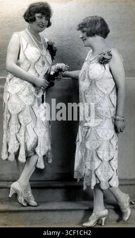 Deux modèles à la mode parisienne de 1925 portant des robes identiques faites du même tissu, richement décorées de perles et de perles. Banque D'Images