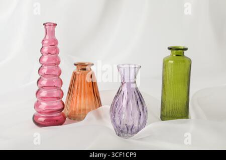 Différents beaux vases en verre sur tissu blanc Banque D'Images
