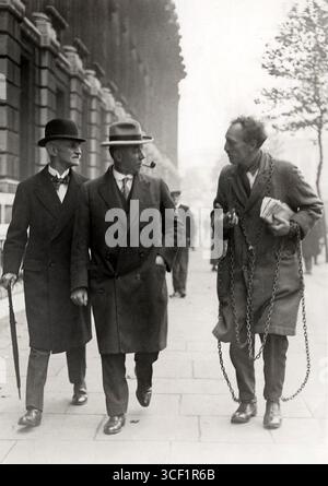 Londres, Angleterre, 1929 : un contribuable ruiné parlant devant le Parlement avec le ministre des Finances anglais et un autre homme, portant des chaînes pour protester. Banque D'Images