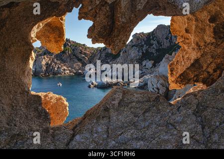 La lumière du soleil illumine la côte rocheuse et les grottes encadrant la mer méditerranée turquoise à Capo ferrato, sardaigne, italie, créant un V à couper le souffle Banque D'Images
