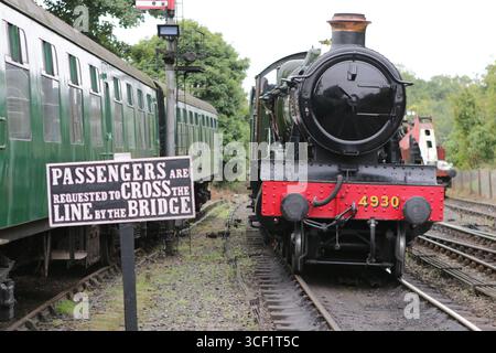 1929 GWR 4930 Hagley Hall du Severn Valley Railway à Bridgnorth Station, Shropshire, à côté d'un panneau indiquant aux passagers de traverser la ligne via un pont. Banque D'Images
