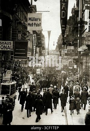 En 1921, une scène de rue animée est capturée sur Petersstrasse lors de la foire commerciale de Leipzig en Allemagne, montrant la foule et l'activité autour de l'événement. Banque D'Images