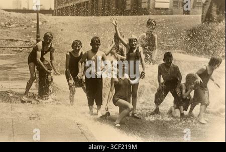 En juillet 1928, les enfants cherchent à se soulager d'une canicule en jouant près d'une bouche d'incendie, essayant de se rafraîchir pendant les températures brûlantes. Banque D'Images