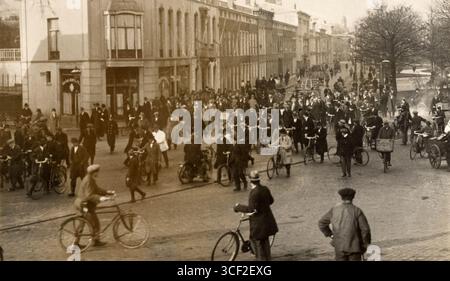 Cette photographie de 1922 représente une descente de police à la Haye, aux pays-Bas, ciblant des maisons dans le district de la gare, où vivaient des voleurs présumés. Des policiers sont vus escorter les détenus à travers Huygenspark, tandis que les résidents du quartier observent l'arrestation. Banque D'Images