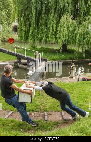 Angleterre, Somerset, Bath, le canal Kennet et Avon, Widcombe Lock et Thimble Mill Lock, couple ouvrant les portes de l'écluse Banque D'Images