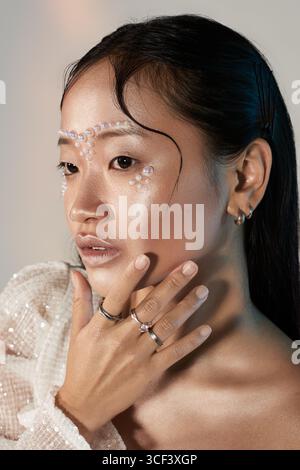 Expression de beauté unique par une jeune femme asiatique présentant le maquillage de perle dans un studio élégant. Banque D'Images