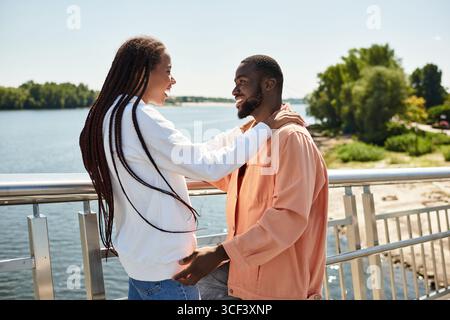 Un couple aimant partage un moment joyeux tout en marchant le long de la rive par une journée ensoleillée. Banque D'Images