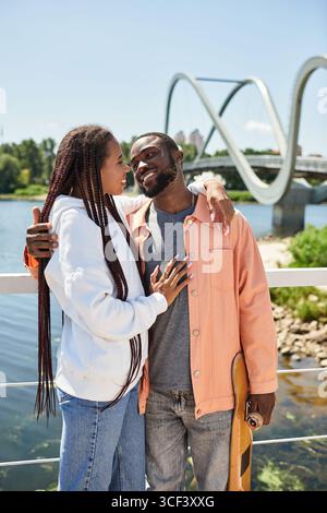 Un jeune couple aime la compagnie de l'autre, embrassant près d'une rivière pittoresque sous le soleil. Banque D'Images