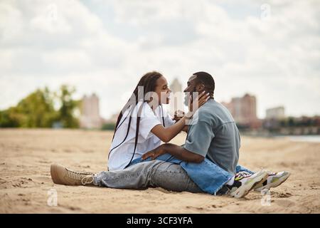 Un couple aimant profite d'une promenade tranquille le long d'une plage sereine, embrassant comme ils se connectent profondément. Banque D'Images