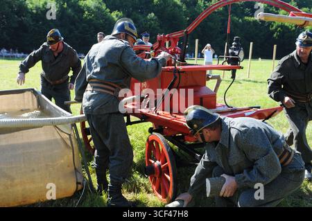 Pompiers utilisant une pompe à main historique avec réservoir d'eau pendant la compétition à Rudawka Rymanowska, Podkarpackie, Pologne Banque D'Images