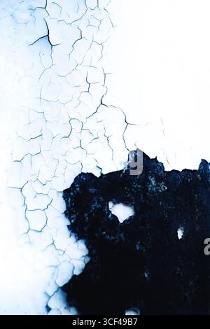Pelage de peinture blanche sur une surface métallique noire, fissures Banque D'Images