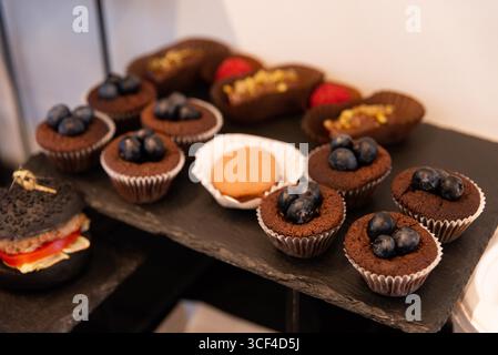 Une délicieuse gamme de friandises au chocolat garnies de myrtilles fraîches est magnifiquement exposée. parfaits pour les fêtes et les rassemblements, ces desserts offe Banque D'Images