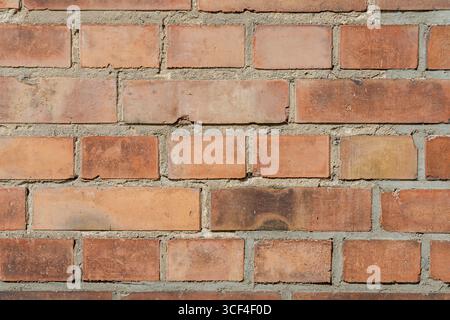 Un gros plan d'un vieux mur de briques montrant des motifs irréguliers, des surfaces altérées, des décolorations, des mperfections et des textures rugueuses. Banque D'Images
