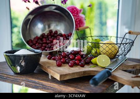 Cerises rouges fraîches pour confiture maison. Sucre, citron vert et citron pour la conservation des fruits. Fond pour confiture maison. Banque D'Images