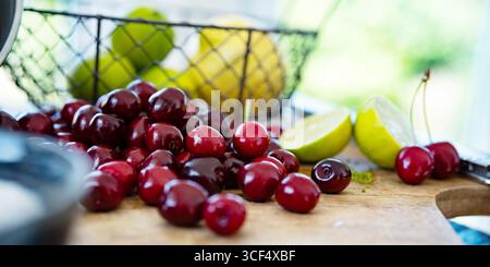 Cerises rouges fraîches pour confiture maison. Sucre, citron vert et citron pour la conservation des fruits. Fond pour confiture maison. Banque D'Images