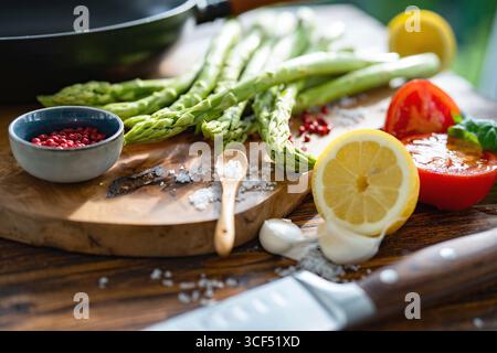 Ingrédients frais pour asperges vertes rôties. Légumes locaux et une poêle en fonte sur une table en bois rustique. Gros plan avec faible profondeur de champ. Banque D'Images