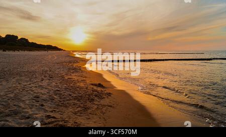 Coucher de soleil sur la plage de Zinnowitz sur l'île d'Usedom avec le ciel rouge vif du soir - spectaculaire paysage côtier de la mer Baltique. Banque D'Images
