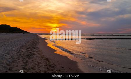 Coucher de soleil sur la plage de Zinnowitz sur l'île d'Usedom avec le ciel rouge vif du soir - spectaculaire paysage côtier de la mer Baltique. Banque D'Images
