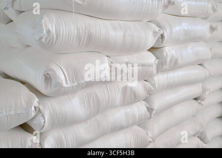 Installation de stockage remplie de sacs empilés de farine de blé dans un entrepôt animé pendant les heures de pointe de distribution Banque D'Images