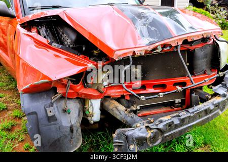 La camionnette rouge présente des dommages importants à l'avant après une collision dans le pare-chocs accidenté, composants exposés. Banque D'Images