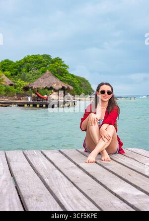 Une jeune femme profitant d'un moment de sérénité sur l'île de Rosario, Carthagène, avec des paysages tropicaux et un quai en bois. Banque D'Images