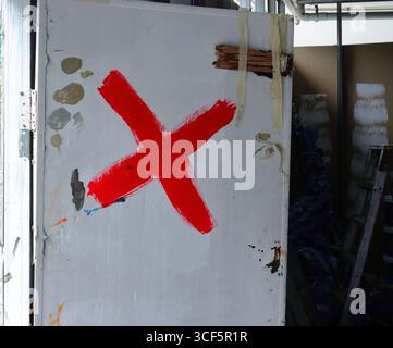 Marque X peinte en rouge sur la porte en bois blanc d'un cellier Banque D'Images
