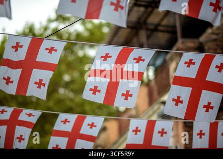 Plusieurs drapeaux géorgiens suspendus à l'extérieur avec un fond flou dans la vieille ville de Tbilissi, Géorgie Banque D'Images