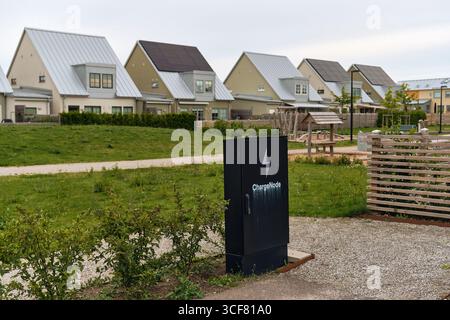 Tygelsjö, Suède ; 4 août 2025 : maisons modernes en rangée suédoises avec toits métalliques, panneaux solaires et station de recharge. Banque D'Images