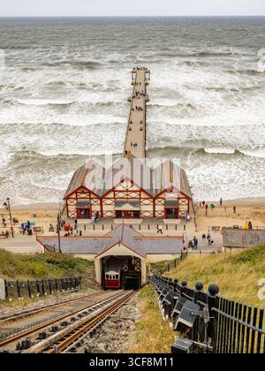 Vue depuis le sommet de la falaise vers le tramway de Saltburn Cliff, un funiculaire équilibré en eau, et la célèbre jetée victorienne, North Yorkshire, Royaume-Uni. Banque D'Images