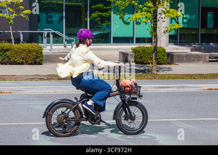Jeune femme conduisant son e-bike à Vancouver sur West 10th Avenue Banque D'Images
