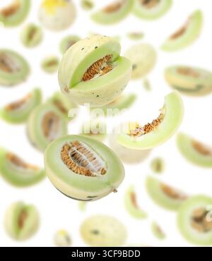 Coupez des melons frais mûrs tourbillonnant dans l'air sur fond blanc Banque D'Images