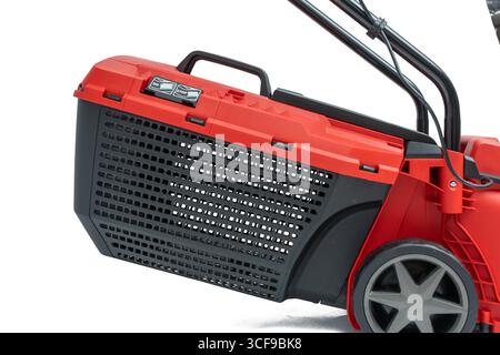 Gros plan du collecteur d'herbe noir avec un couvercle rouge d'une tondeuse à gazon. Avec poignée de transport et fentes de ventilation, isolé sur un fond blanc. Banque D'Images