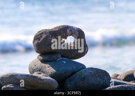 Roche volcanique naturellement érodée avec un trou, reposant sur d'autres pierres près du rivage de l'île de Seymour Nord, îles Galápagos, Équateur. Banque D'Images