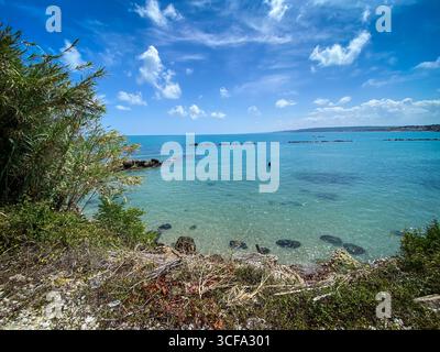 Eaux turquoise Adriatique entourant des brise-lames en pierre près de Rocca San Giovanni côte rocheuse, paysage verdoyant sous la lumière du soleil Banque D'Images
